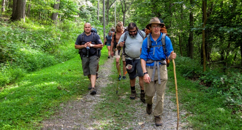 a group of veterans navigate a grassy trail on an outward bound expedition 